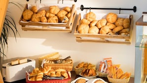 A breakfast buffet with various breads and pastries displayed in baskets and trays. - Allyouneed Hotel Salzburg (Salzburg)
