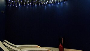 A dark room with a row of white chairs and a red vase on a table. - Hotel Bienestar Termas de Monção (Monção)