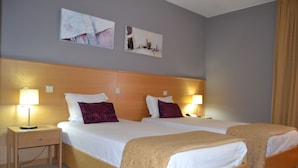 A hotel room with two beds, a wooden headboard, bedside lamps, and artwork on the wall. - Hotel Bienestar Termas de Monção (Monção)