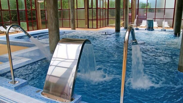 A hot tub with water jets, surrounded by a tiled deck and large windows. - Hotel Bienestar Termas de Monção (Monção)