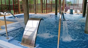 Un jacuzzi con chorros de agua, rodeado por una terraza empaveda y amplias ventanas.