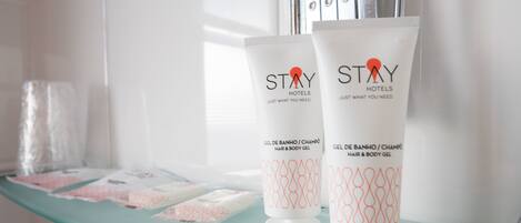 Two bottles of Stay Hotels hair and body gel on a glass shelf.