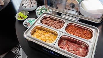 A buffet with various food options including eggs, beans, and bacon.