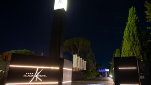 A hotel entrance with a prominent clock tower, a sign for the Black Hotel, and a pathway leading to the building. - Black Hotel (Rome)