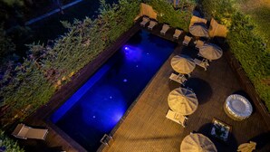 An outdoor swimming pool with a wooden deck, surrounded by lush greenery and equipped with sun loungers and umbrellas. - Black Hotel (Rome)