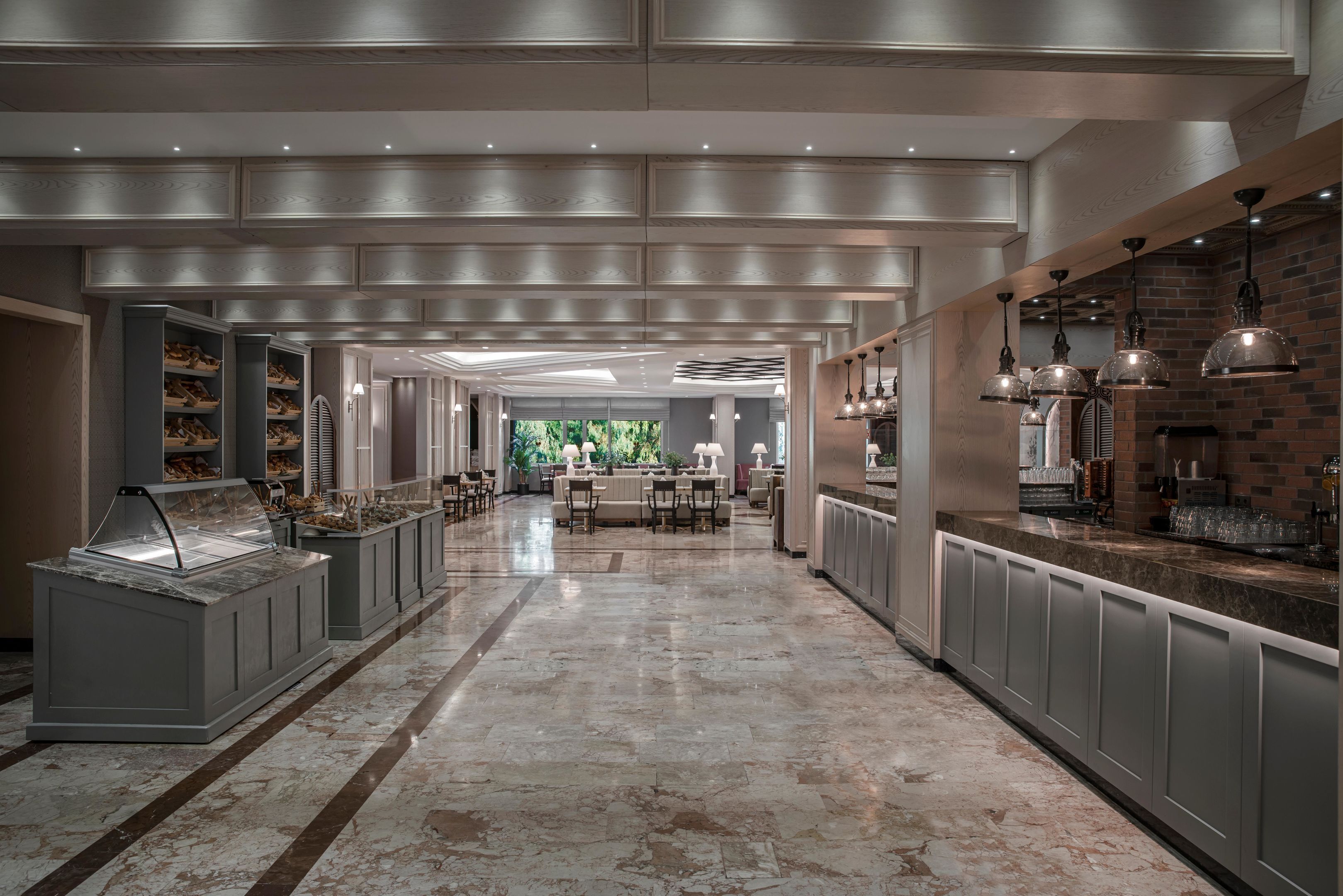 A spacious hotel lobby with a marble floor, a central seating area, and a view of the outdoors.