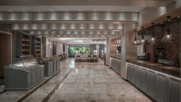 A spacious hotel lobby with a marble floor, a central seating area, and a view of the outdoors.