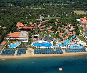 Een luchtend uitzicht op een resort met meerdere zwembaden, een strand en een waterpark.