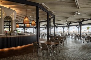 Un restaurante con una zona de bar, varias mesas y lámparas colgantes.