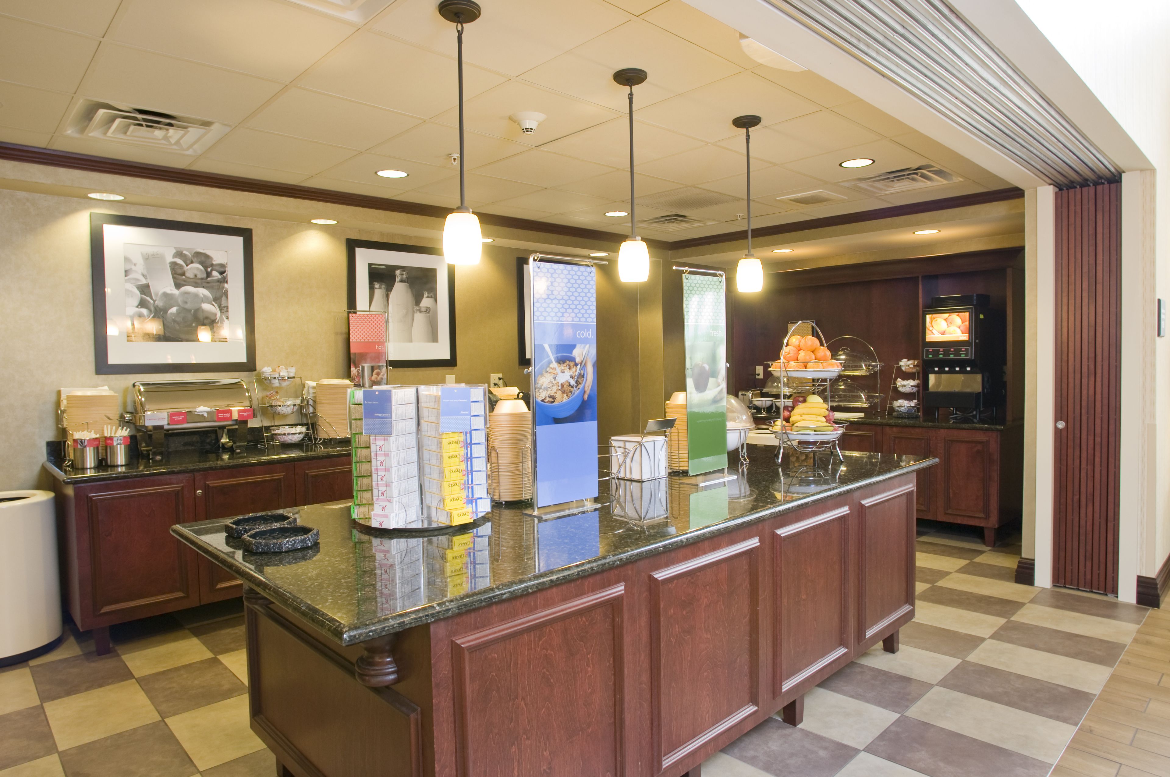 A hotel lobby with a reception desk, framed pictures on the wall, and a vending machine.