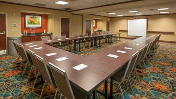 A conference room with a long table, chairs, a whiteboard, and a carpeted floor.