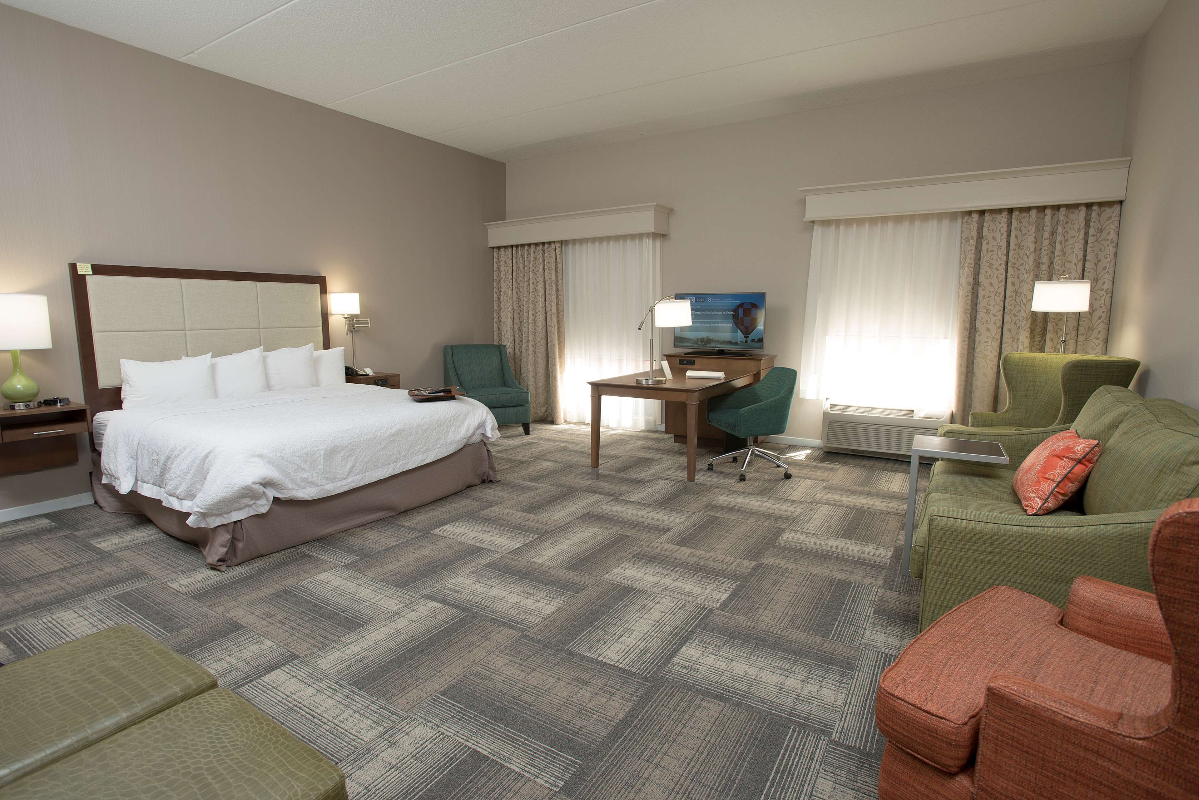A hotel room with a large bed, a desk, two armchairs, and a sofa.