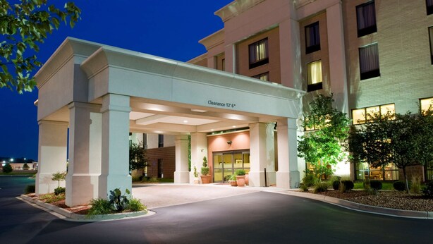 A hotel entrance with a covered area, a clear sign indicating a 12' clearance, and a well-lit facade. - Hampton Inn & Suites Cincinnati-Union Center (West Chester)