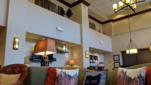 A hotel lobby with a seating area, wall-mounted lamps, and a chandelier. - Hampton Inn & Suites Cincinnati-Union Center (West Chester)
