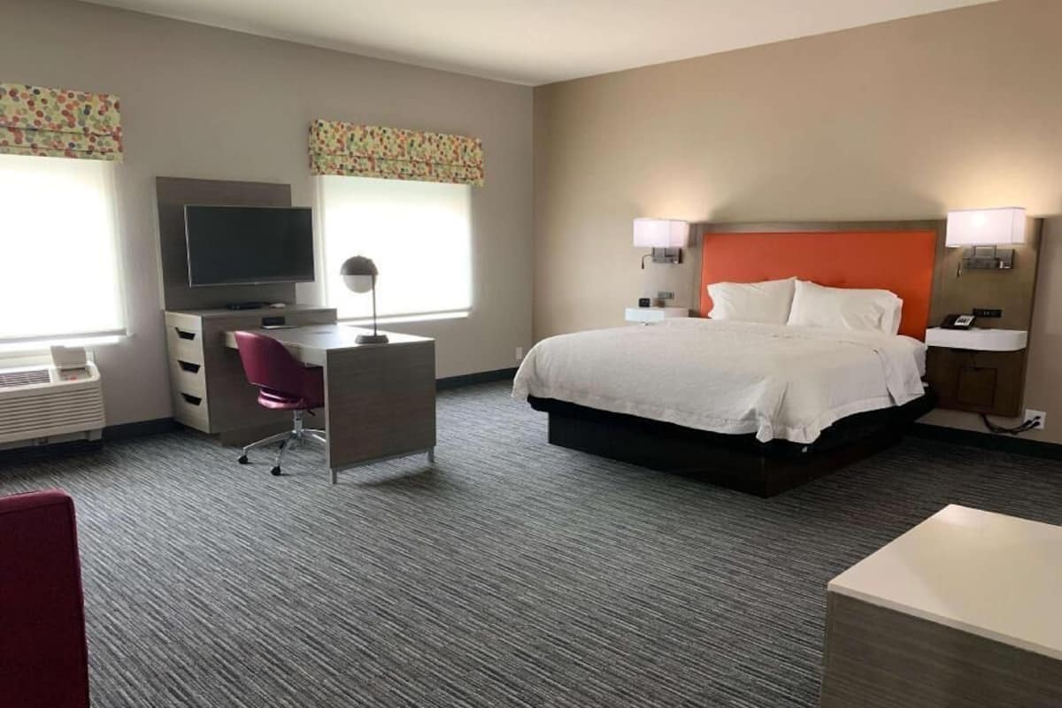 A hotel room with a bed, desk, chair, television, and two bedside lamps.