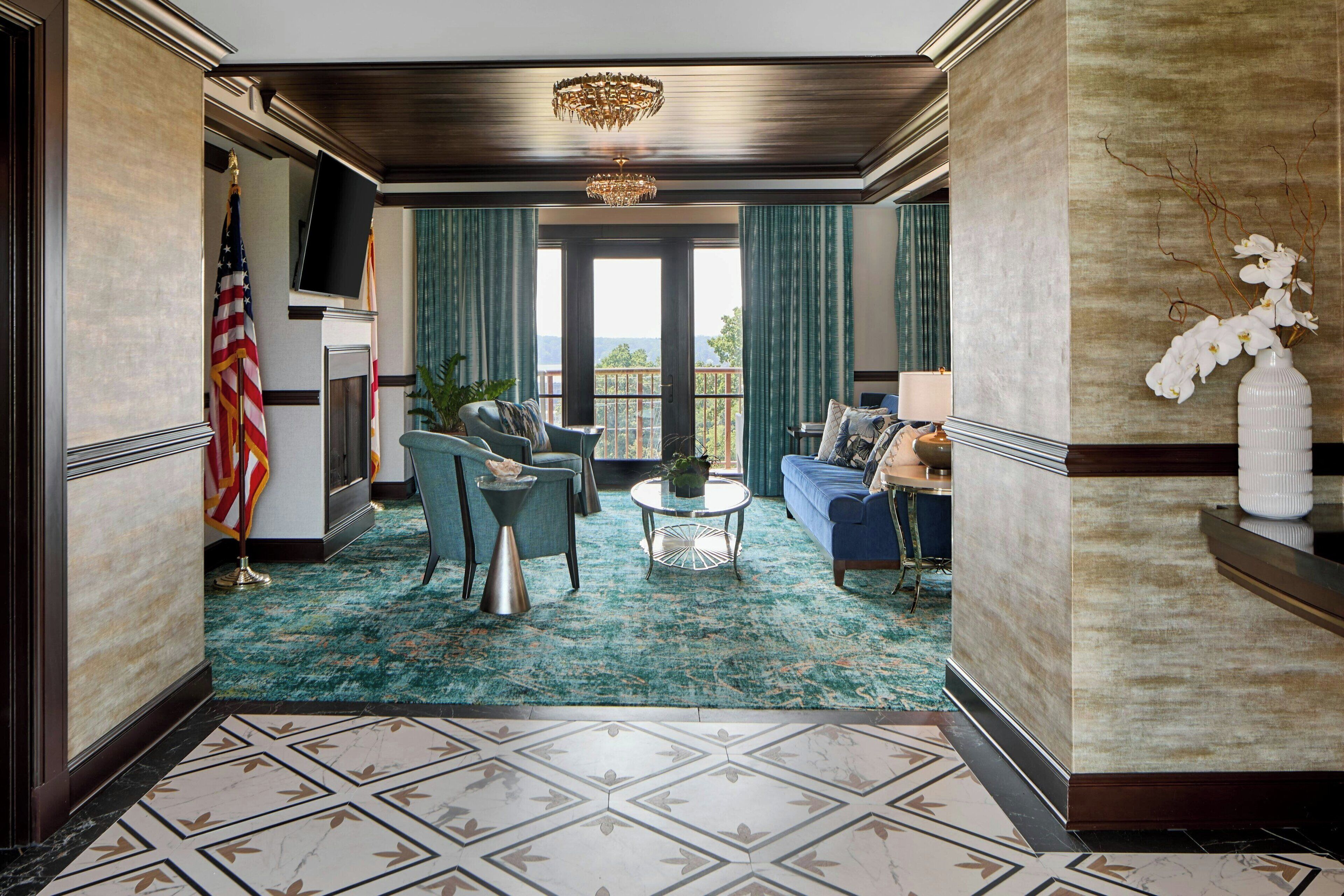 A lobby with a blue sofa, a round coffee table, and a chandelier.