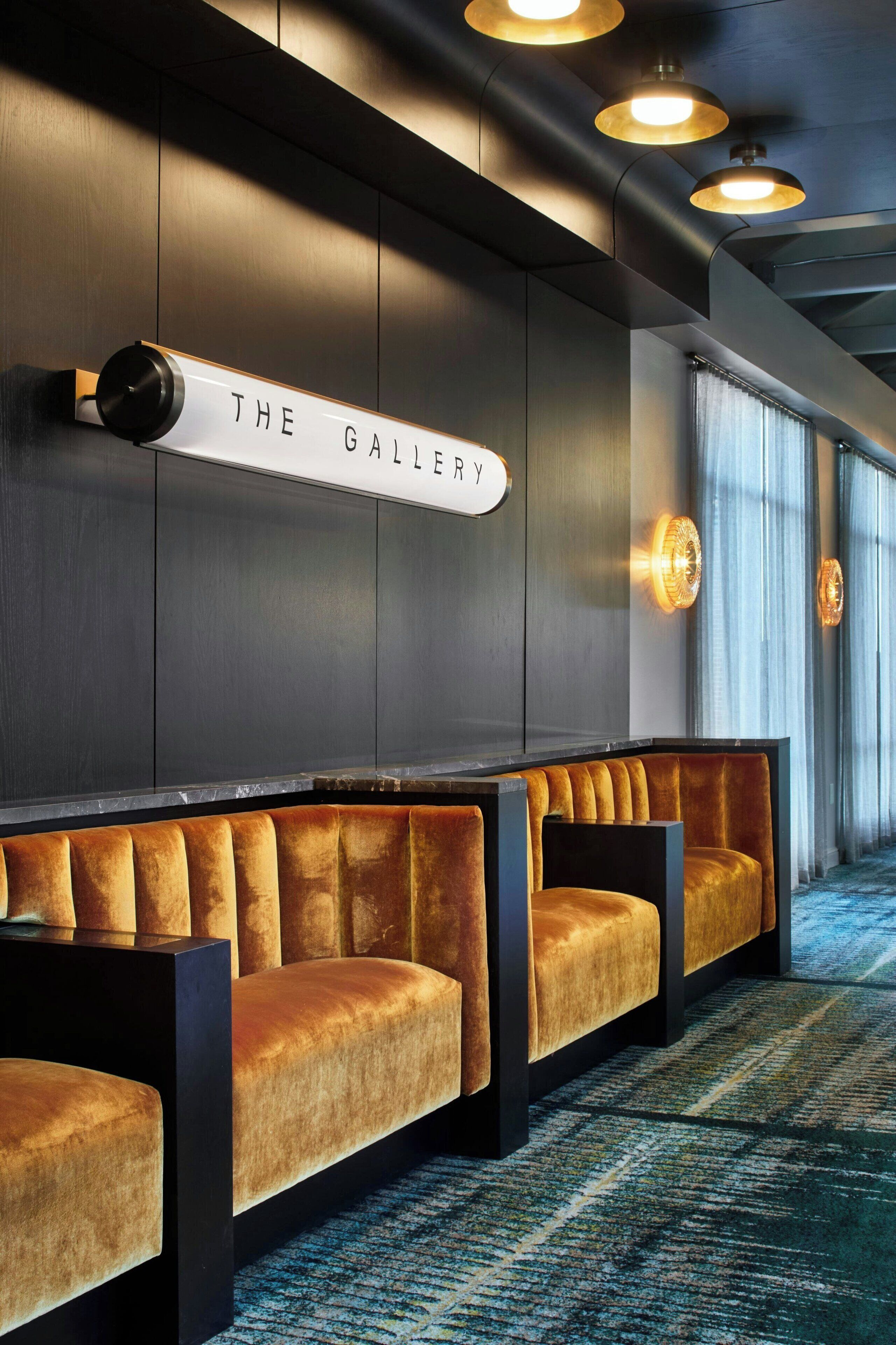 Un moderno vestíbulo de hotel con una recepción, un letrero que dice "The Gallery" y cómodas zonas de estar.
