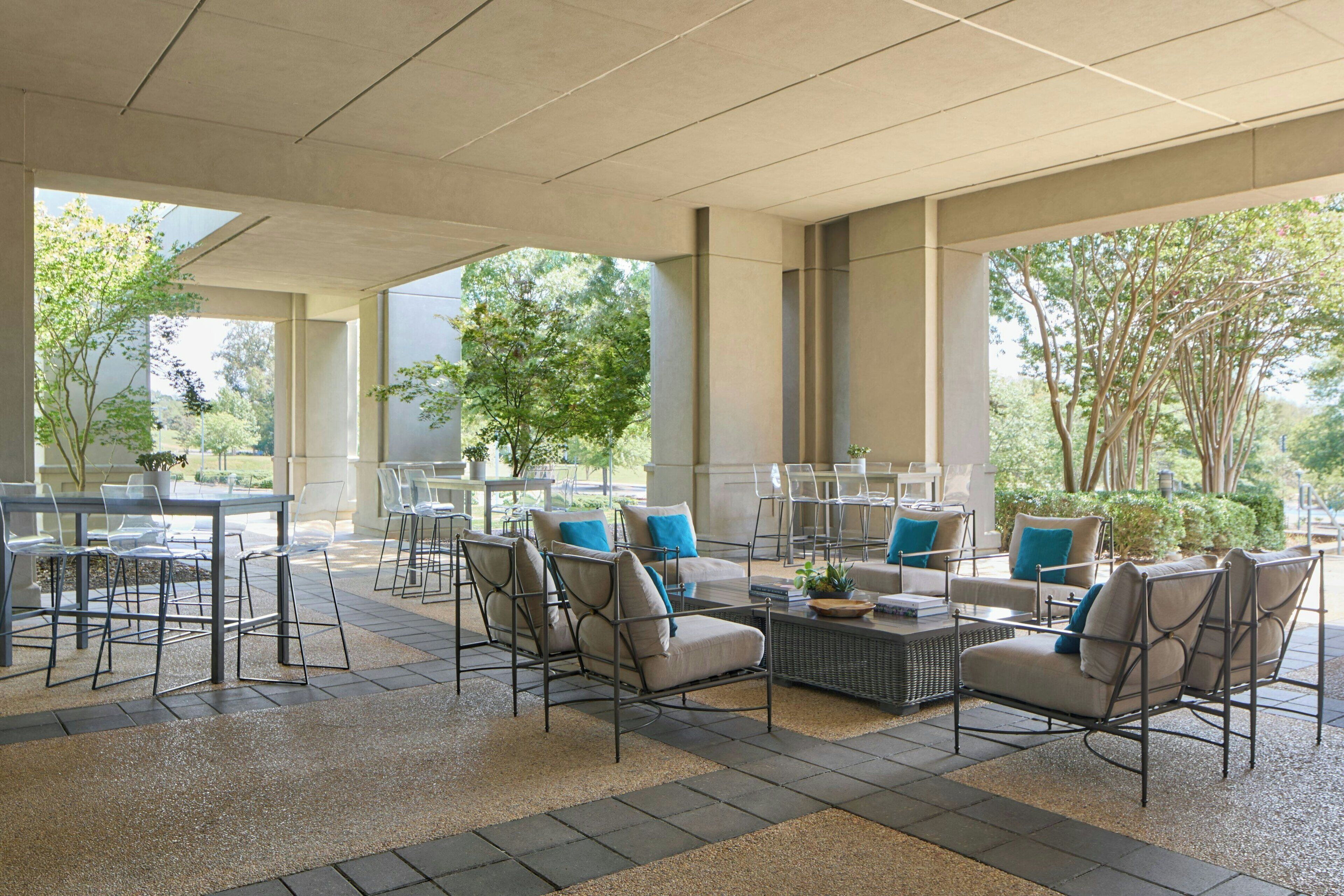 An outdoor seating area with tables and chairs, a coffee table, and potted plants.