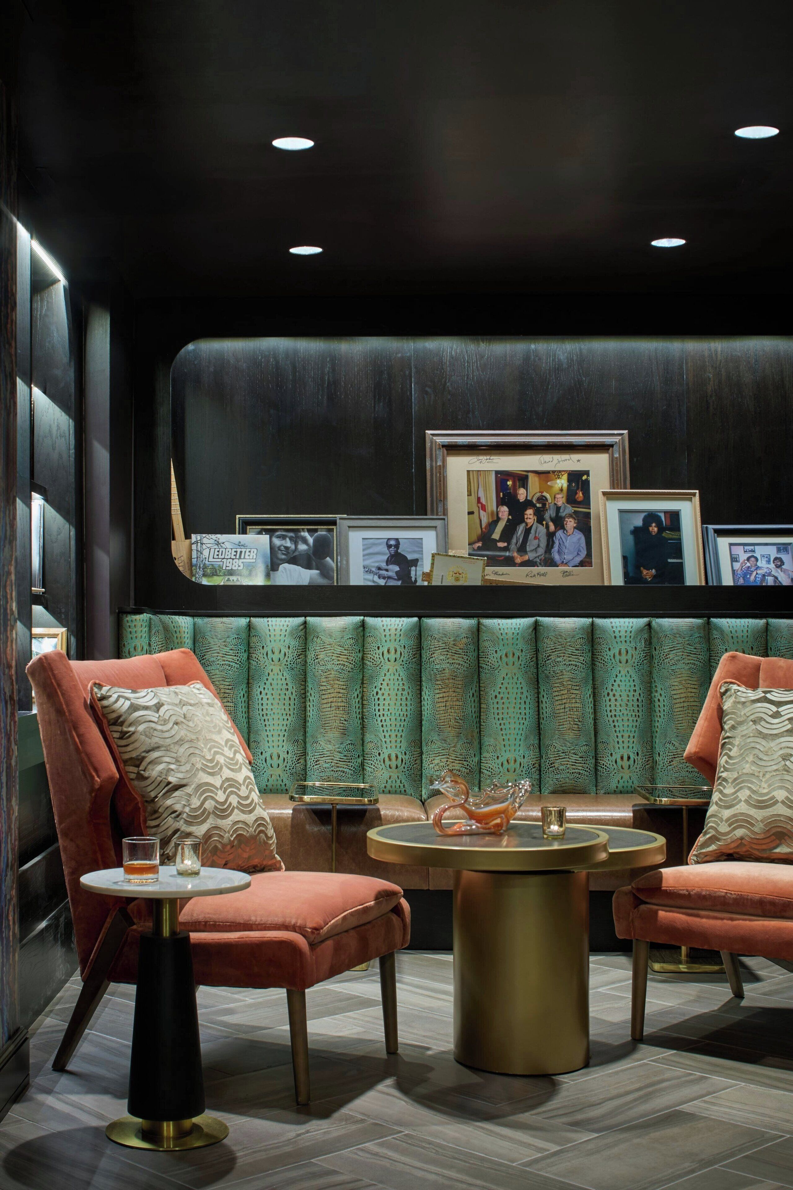 A modern lounge area with two plush armchairs, a round gold table, and a green patterned bench.