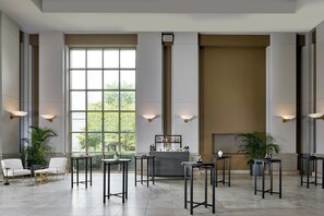 A spacious lobby with a bar area, seating arrangements, and large windows providing natural light.