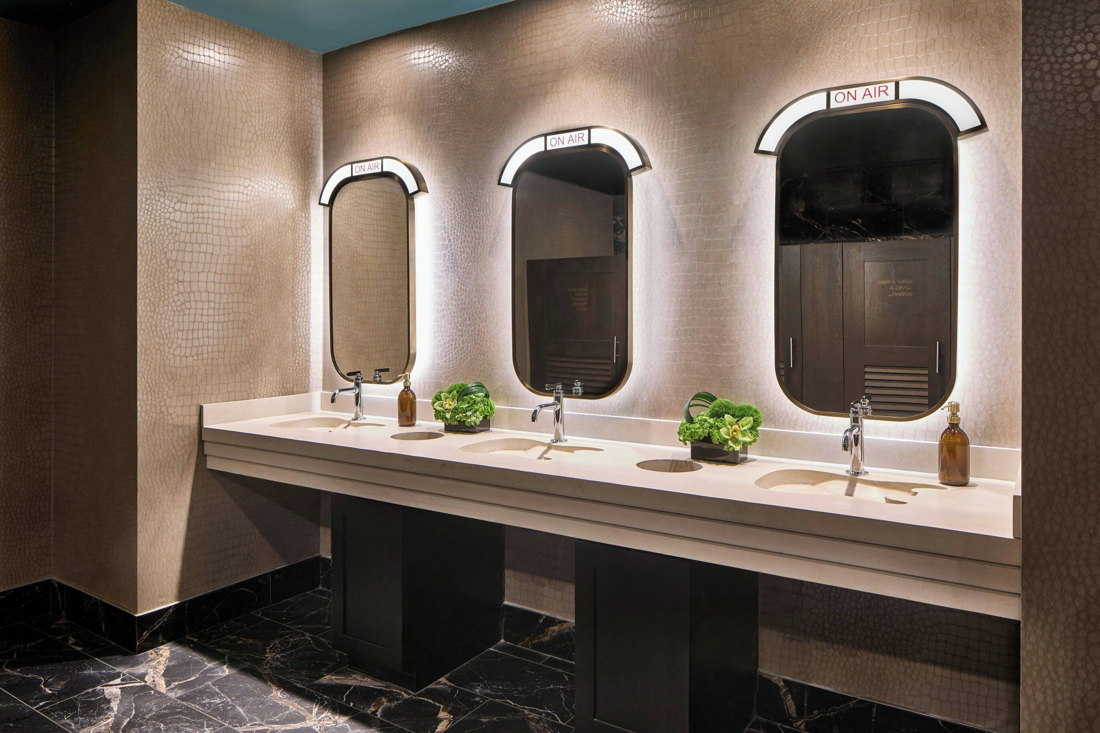 A modern bathroom with three sinks, each with a mirror and labeled "ON AIR".
