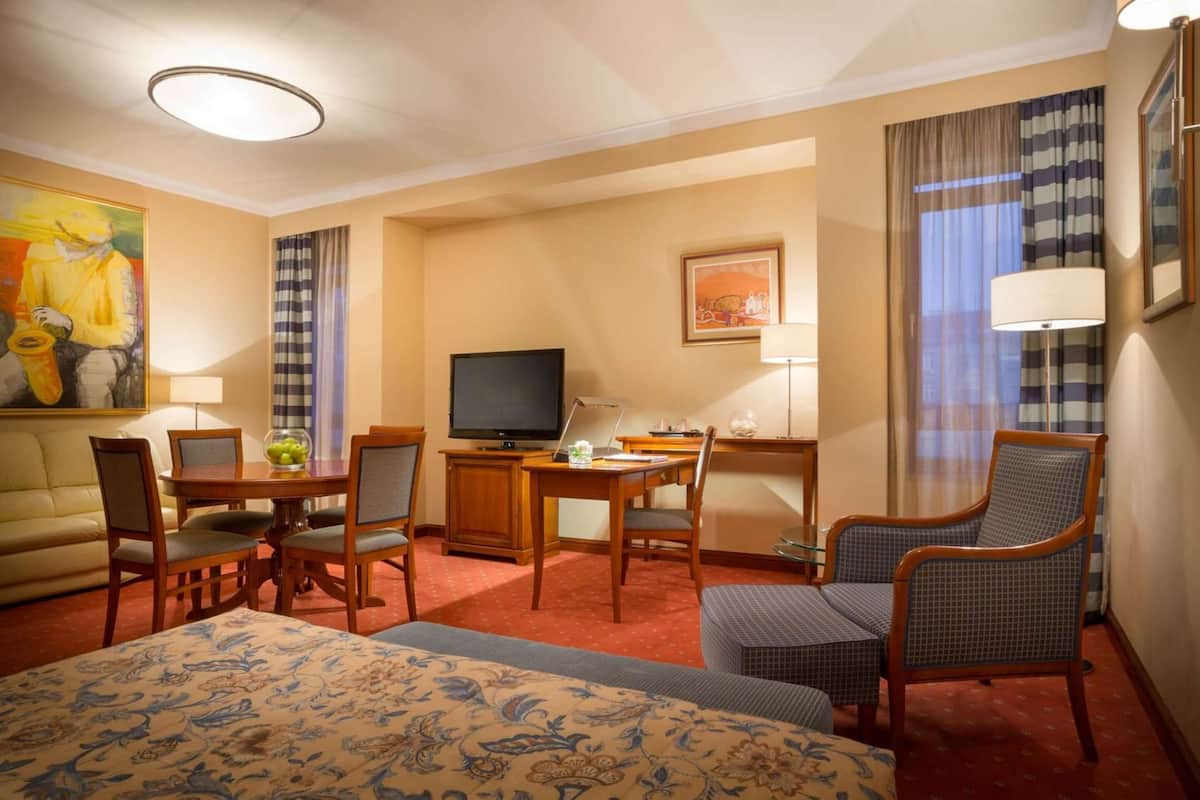A hotel room with a bed, a desk, a television, a chair, and a sofa.