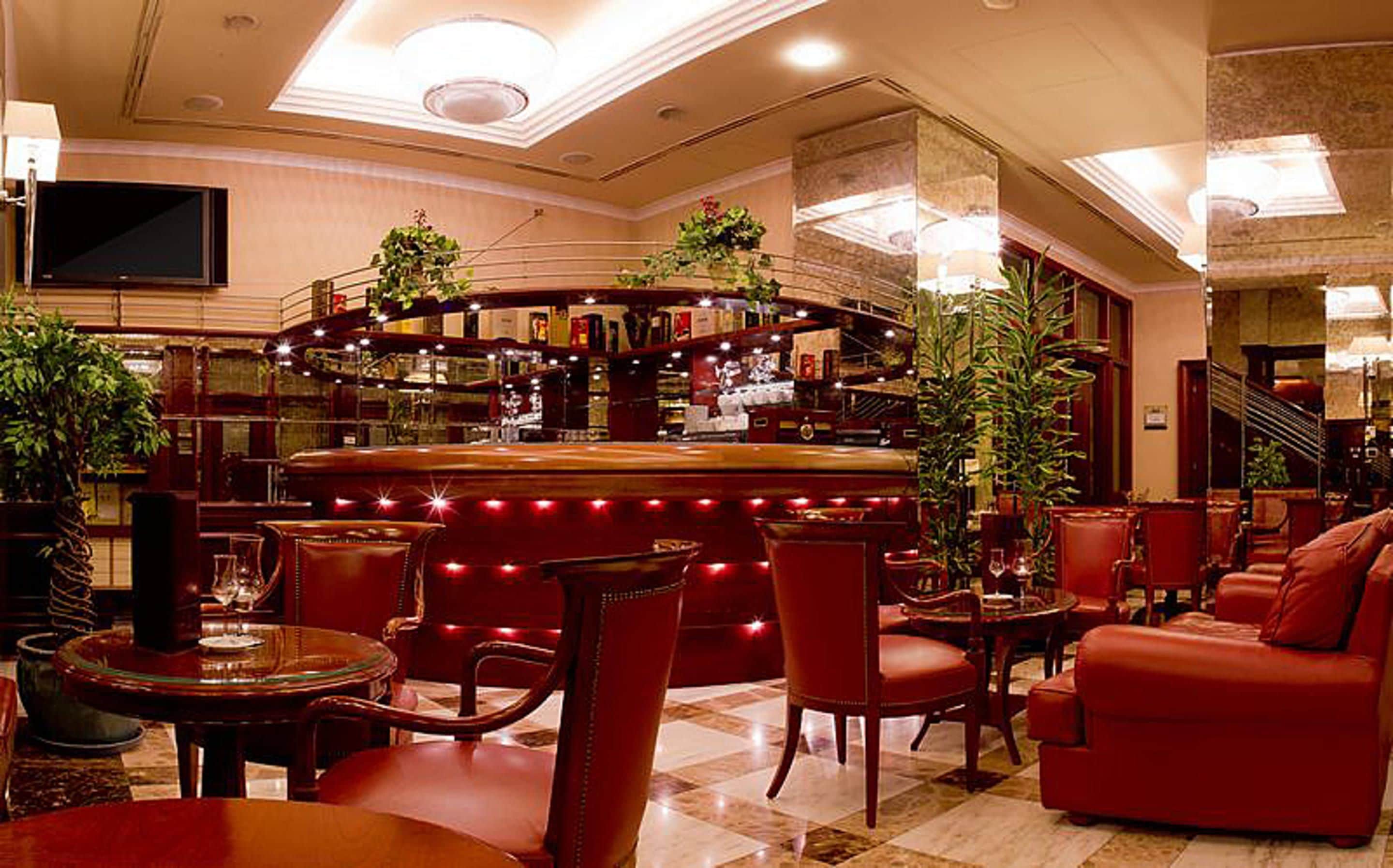 A bar area with a curved counter, multiple seating options including chairs and a sofa, and a television mounted on the wall.