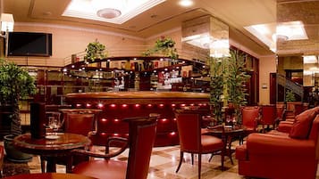 A bar area with a curved counter, multiple seating options including chairs and a sofa, and a television mounted on the wall.