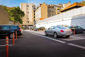 Un parking avec plusieurs voitures et un mur blanc orné de bandes orange.