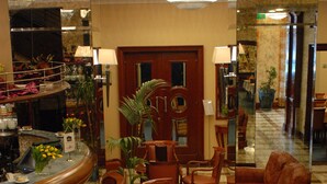 Un hall d’entrée comprenant un comptoir de réception, un espace détente et un miroir qui reflète l’ensemble de la pièce.