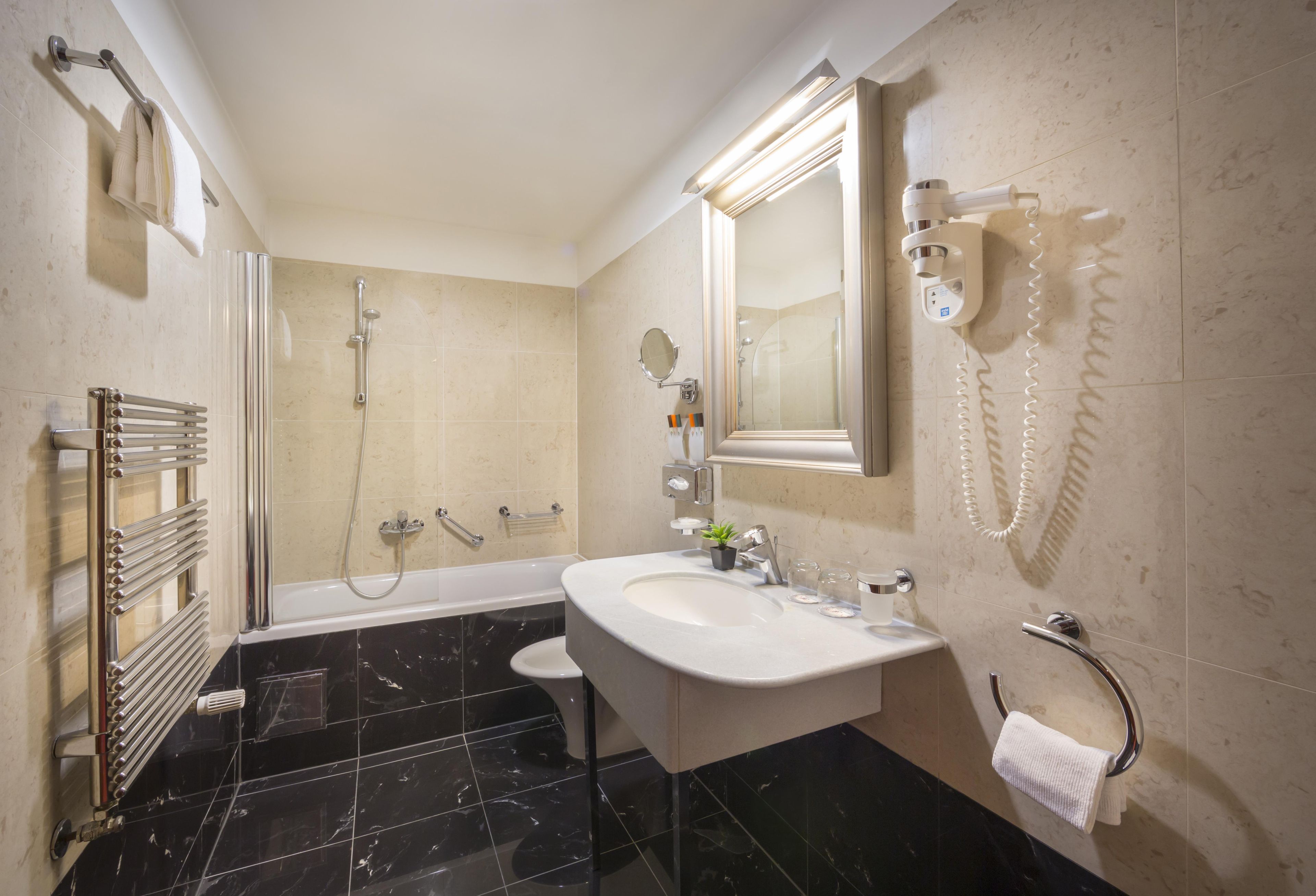 A modern bathroom with a bathtub, a shower, a sink, and a toilet.