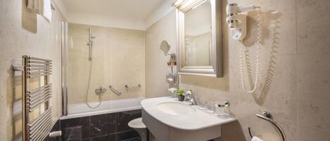 A modern bathroom with a bathtub, a shower, a sink, and a toilet.