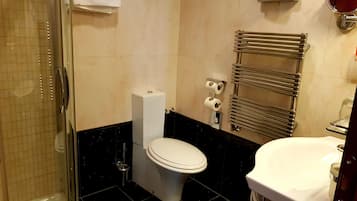 A bathroom with a toilet, a sink, a towel rack, and a shower.
