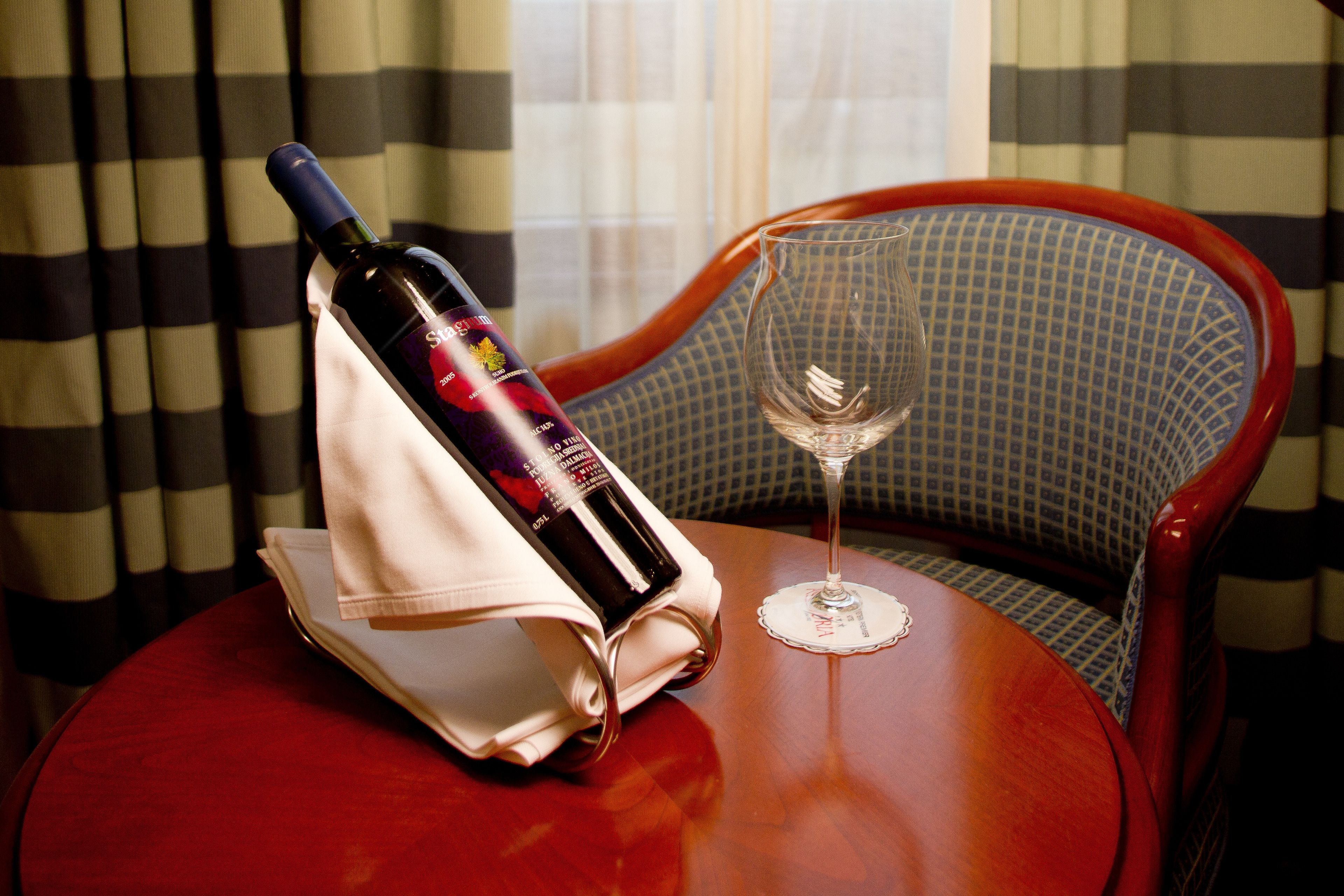 A table with a bottle of wine and a wine glass on a round table.