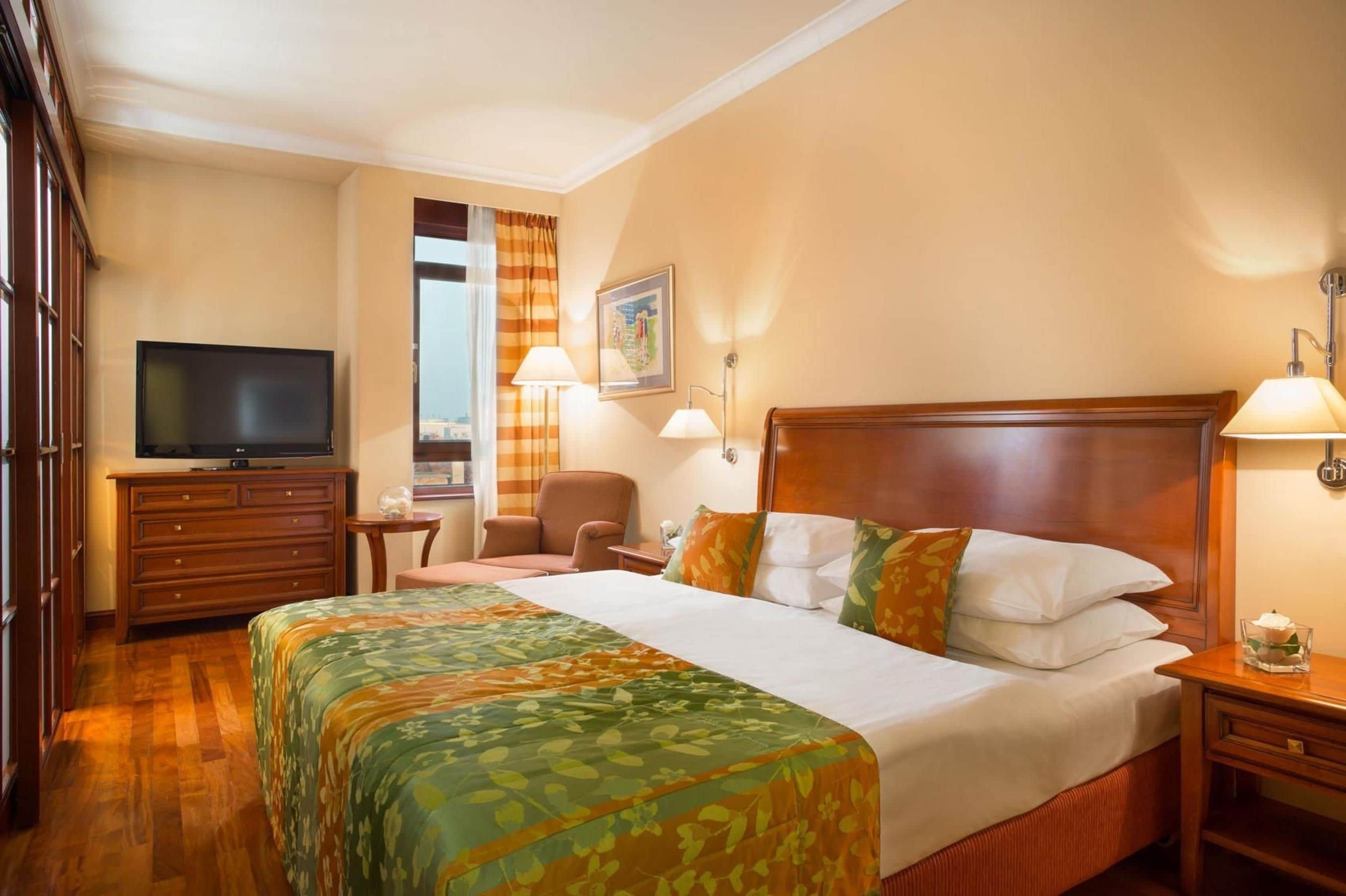 Ein Hotelzimmer mit Bett, Fernseher, Schreibtisch und Stuhl.