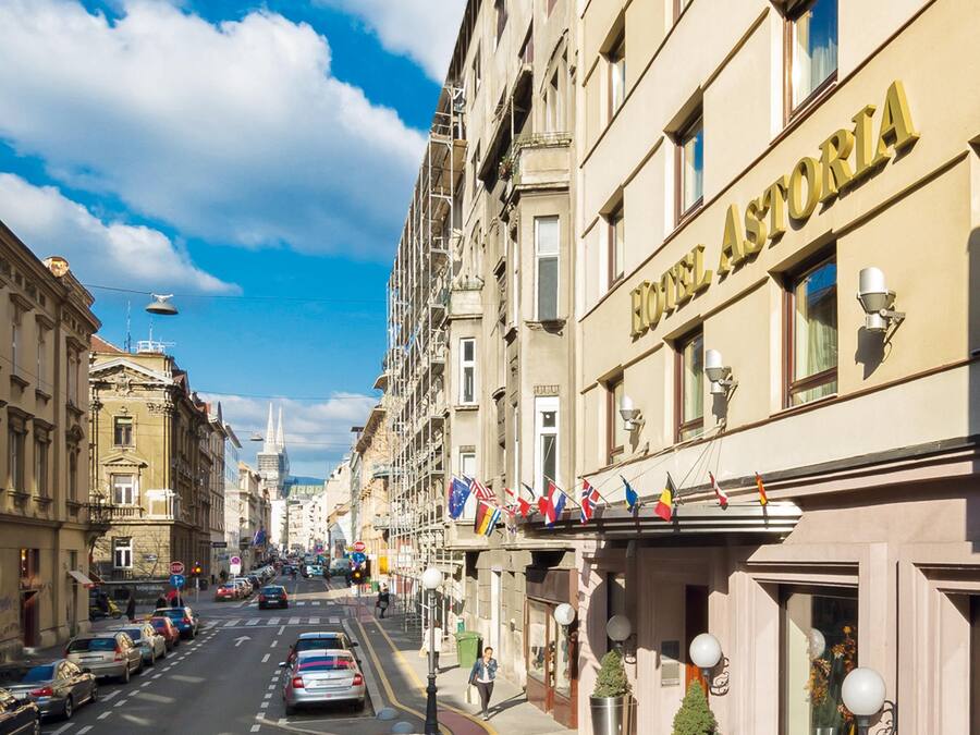 A hotel named 'HOTEL ASTORIA' with a clear view of the street and parked cars.