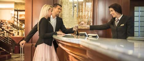 A reception area with a marble counter, a chandelier, and a check-in desk.