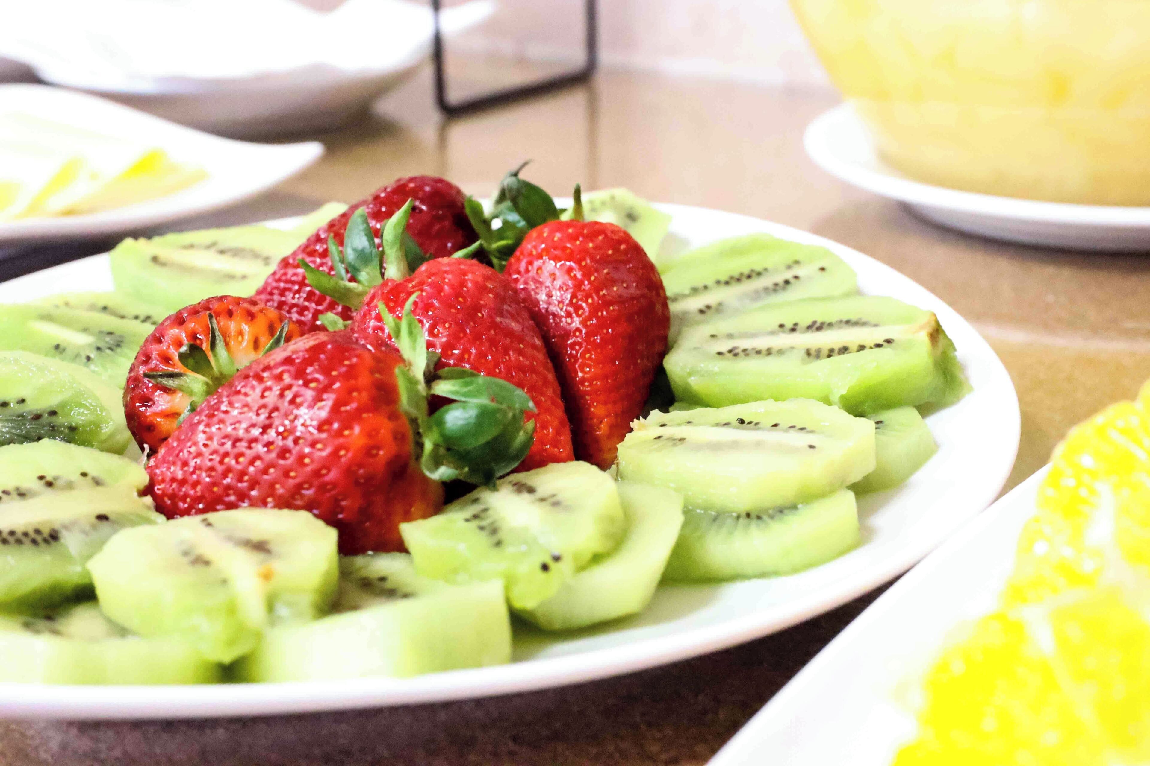 A plate of sliced strawberries and kiwi arranged on a white plate.