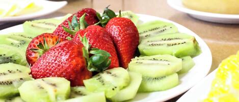 A plate of sliced strawberries and kiwi arranged on a white plate.