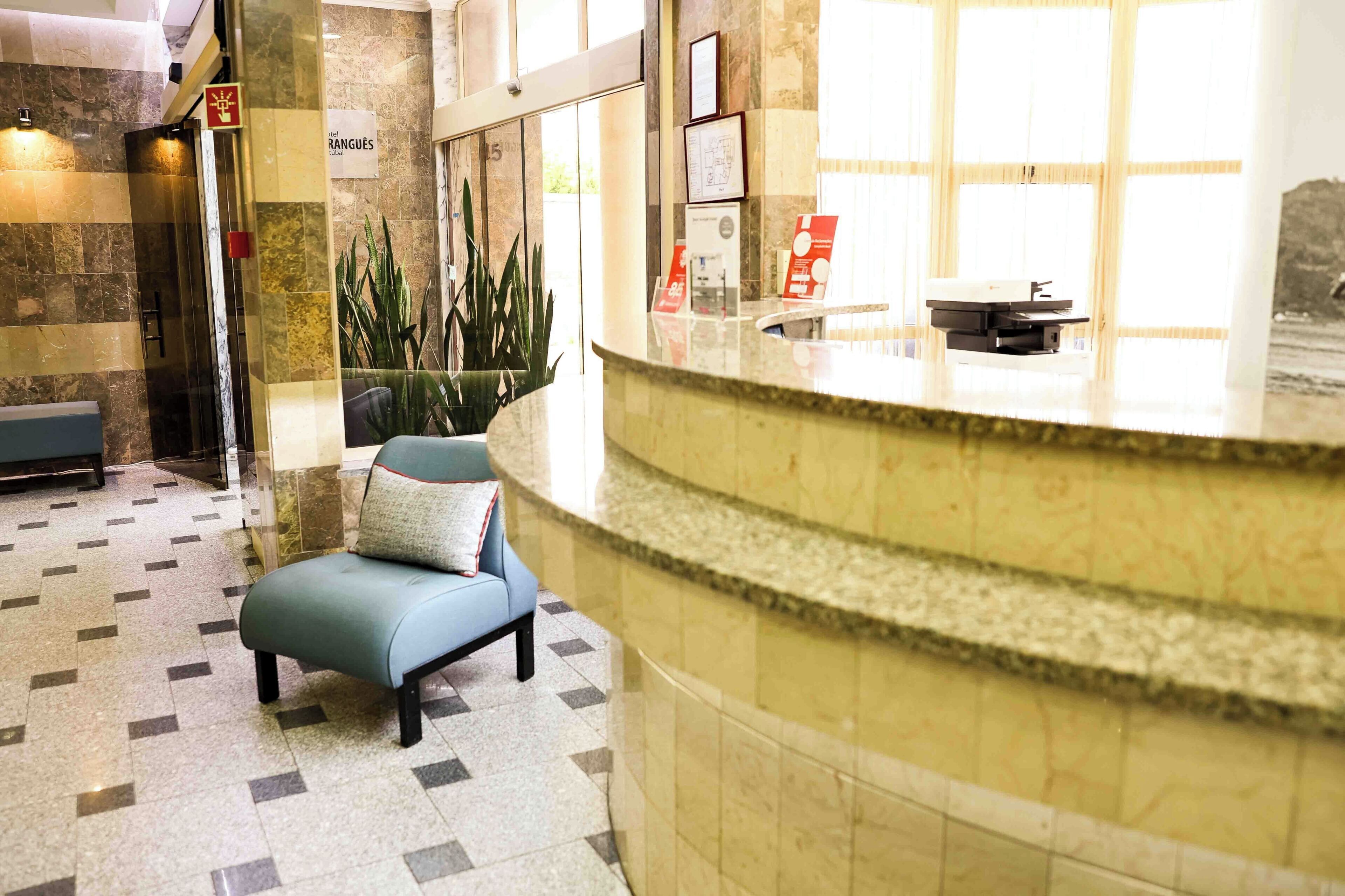 A lobby with a reception desk, a blue cushioned seating area, and a tiled floor.