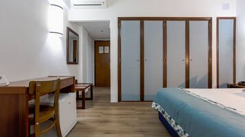 Un dormitorio con una cama, un escritorio, una silla, un armario y una mesita.