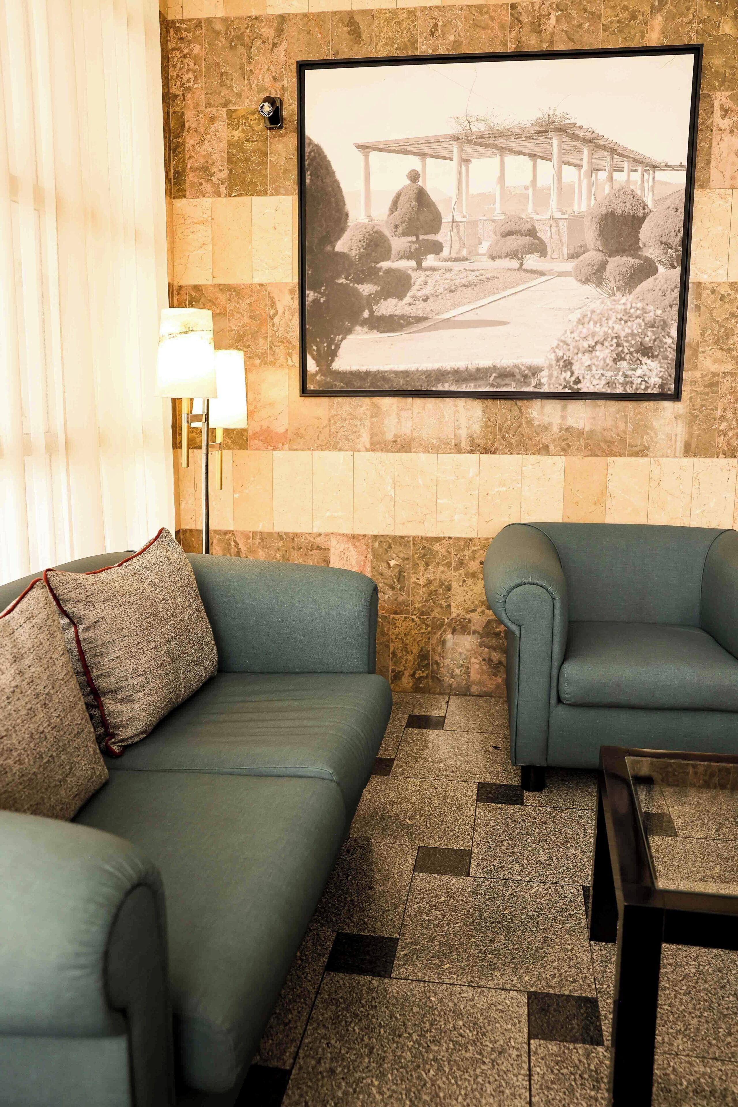 A living room with two sofas, a lamp, a framed picture on the wall, and a patterned floor.