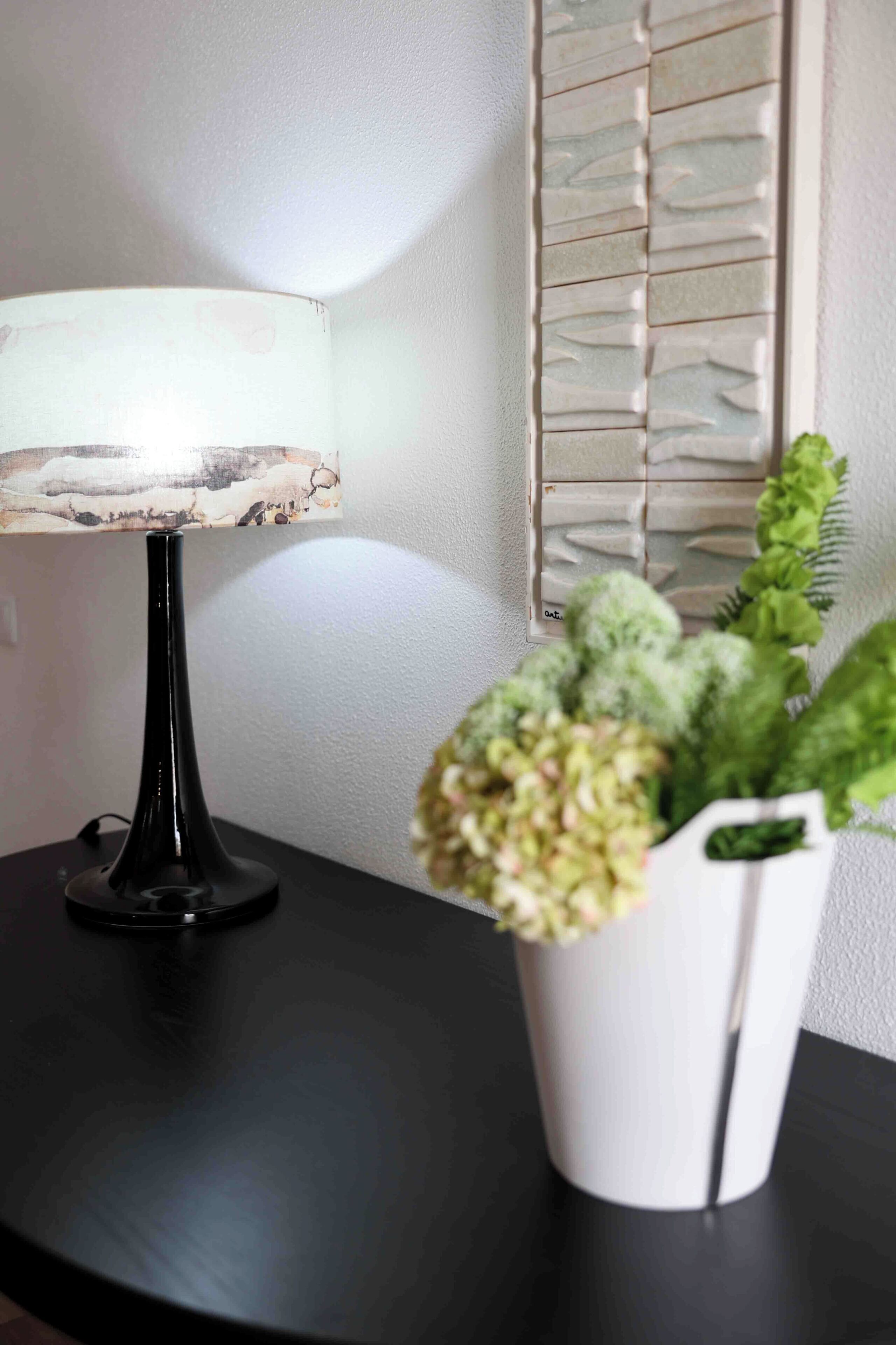 A table with a lamp and a potted plant.