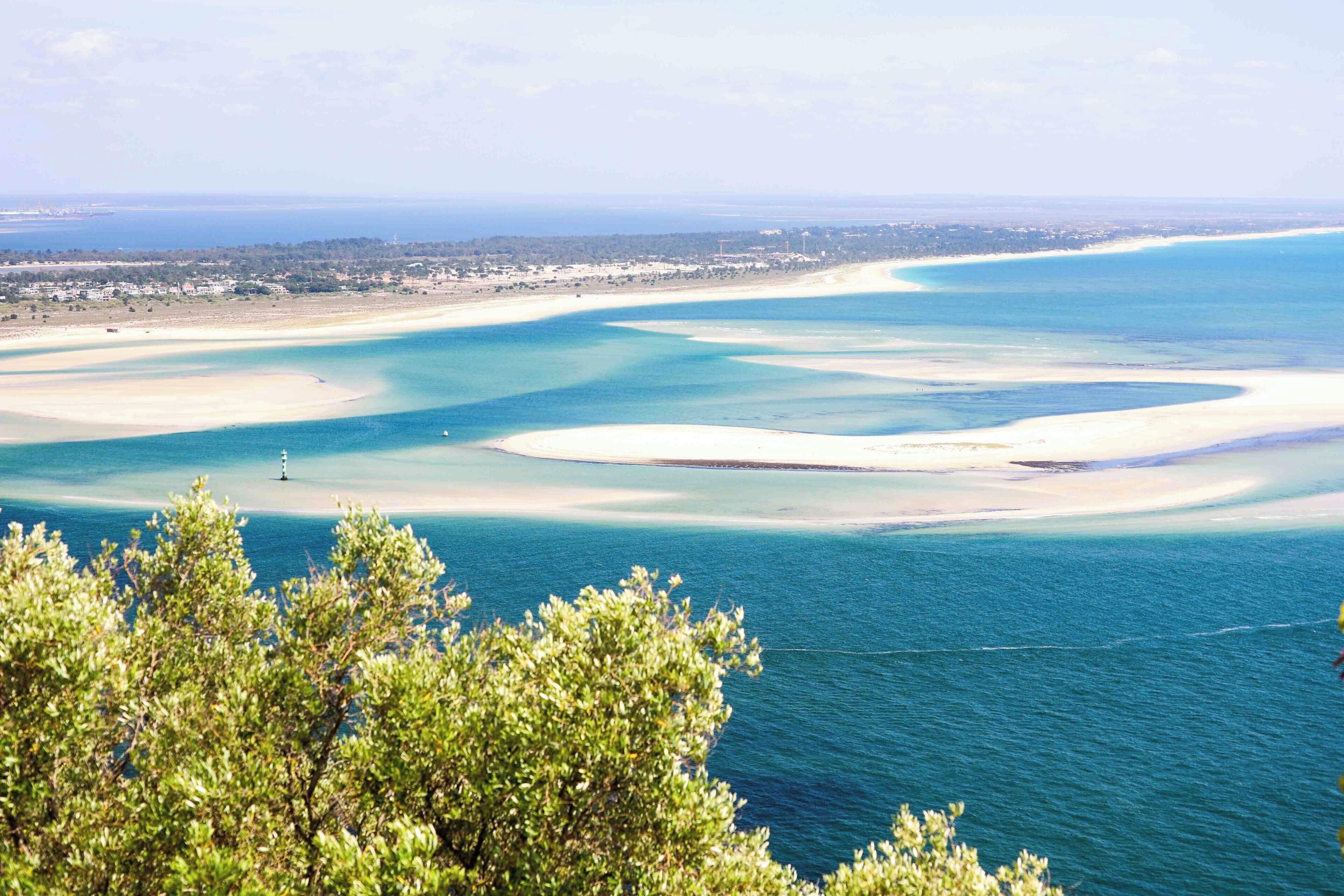 Un paisaje costero con aguas azul turquesa, playas de arena y un pueblo lejano.