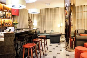 Un rebedor modern d'hotel amb una zona de bar, seients i una planta decorativa.