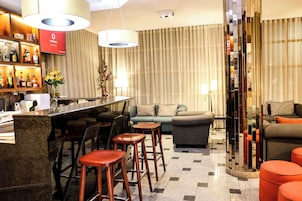 Un moderno vestíbulo de hotel con área de bar, asientos y una planta decorativa.