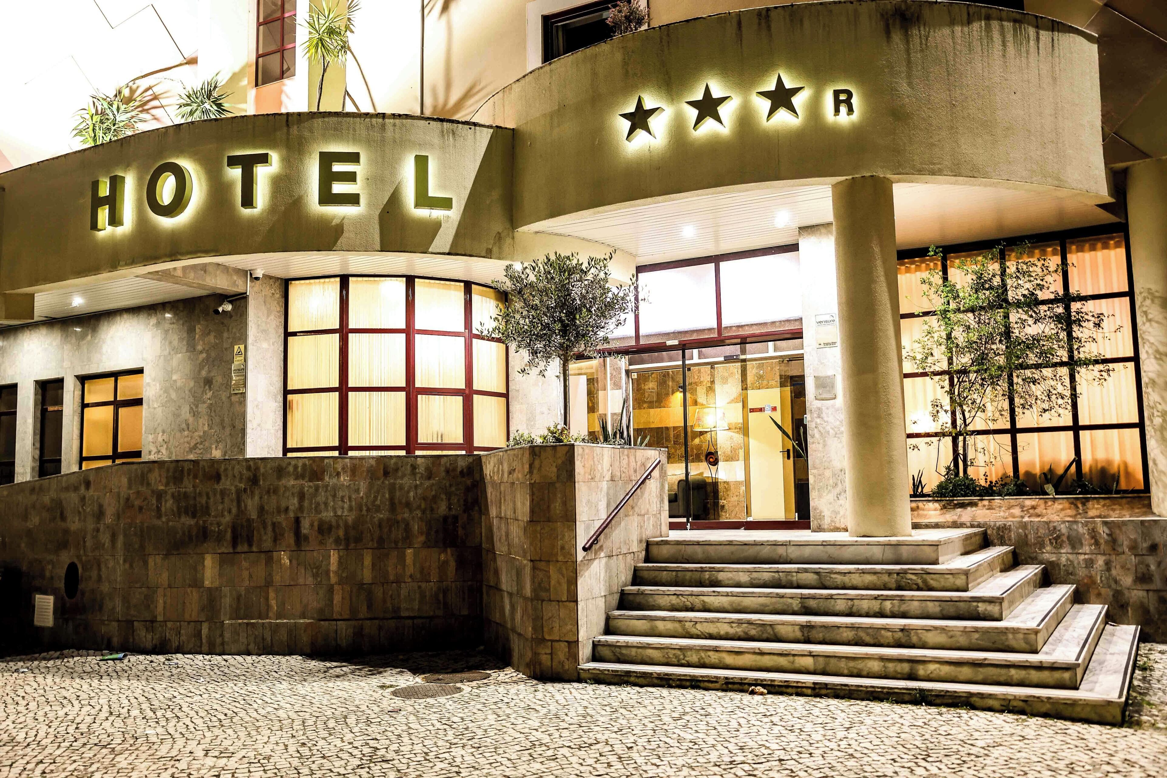 A hotel entrance with a sign, a staircase, and a large window.
