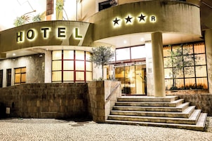 A hotel entrance with a sign, a staircase, and a large window.