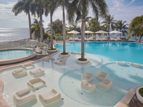 Una piscina al aire libre, sombrillas, sillones reclinables de piscina