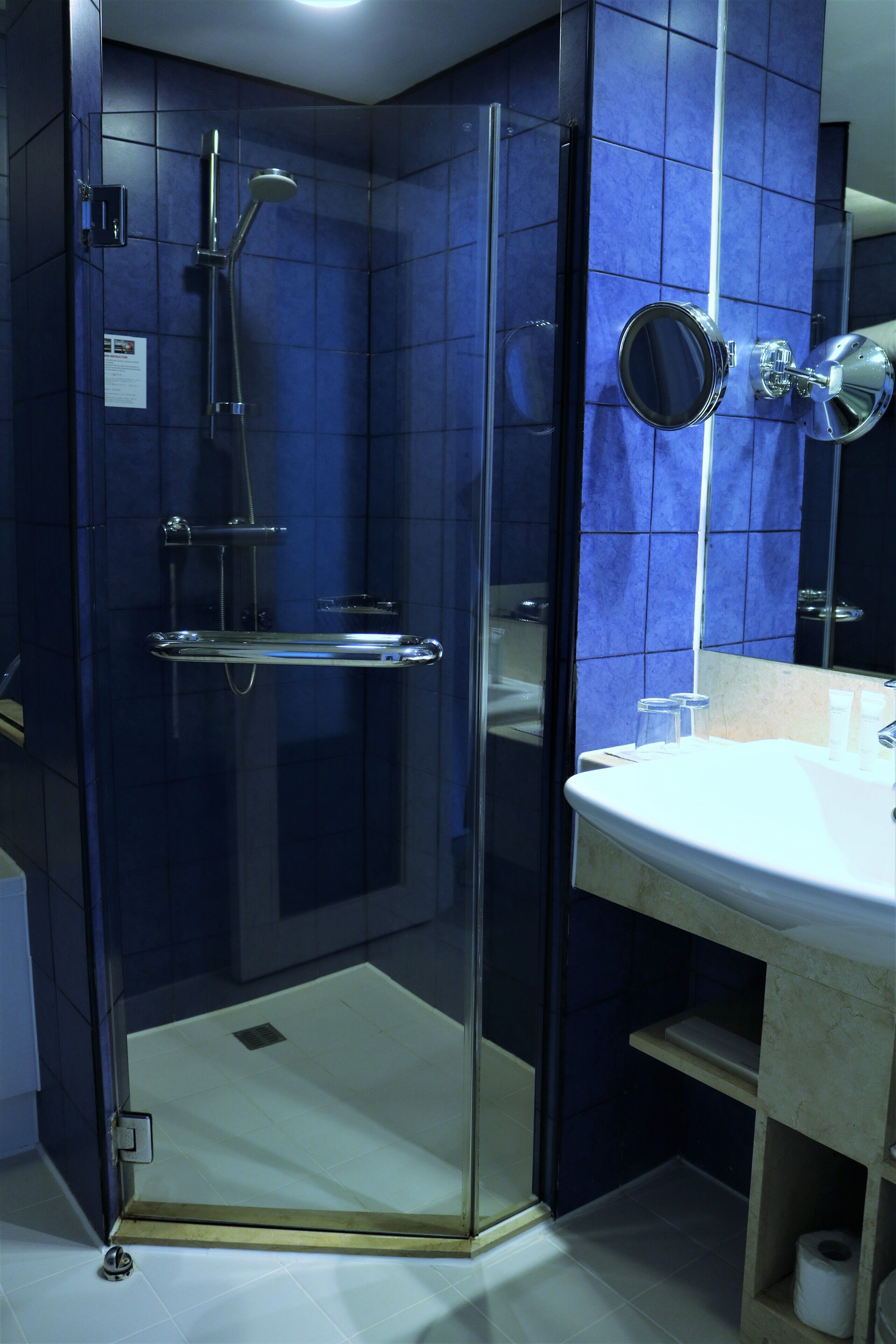 A bathroom with a glass-enclosed shower, a white sink, and a mirror.